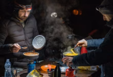 Zwei Motorradfahrer kochen im Dunklen draußen